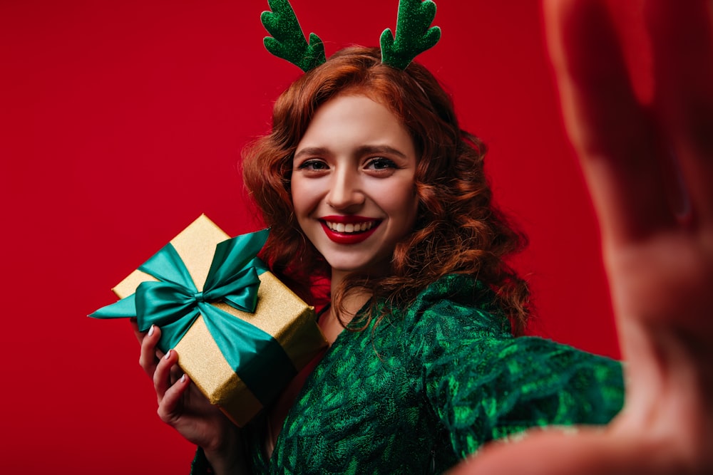 a woman wearing reindeer antlers holding a present