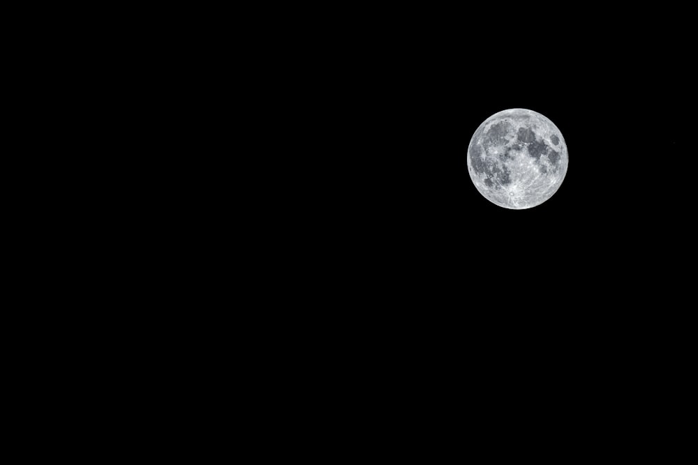 a full moon is seen in the dark sky