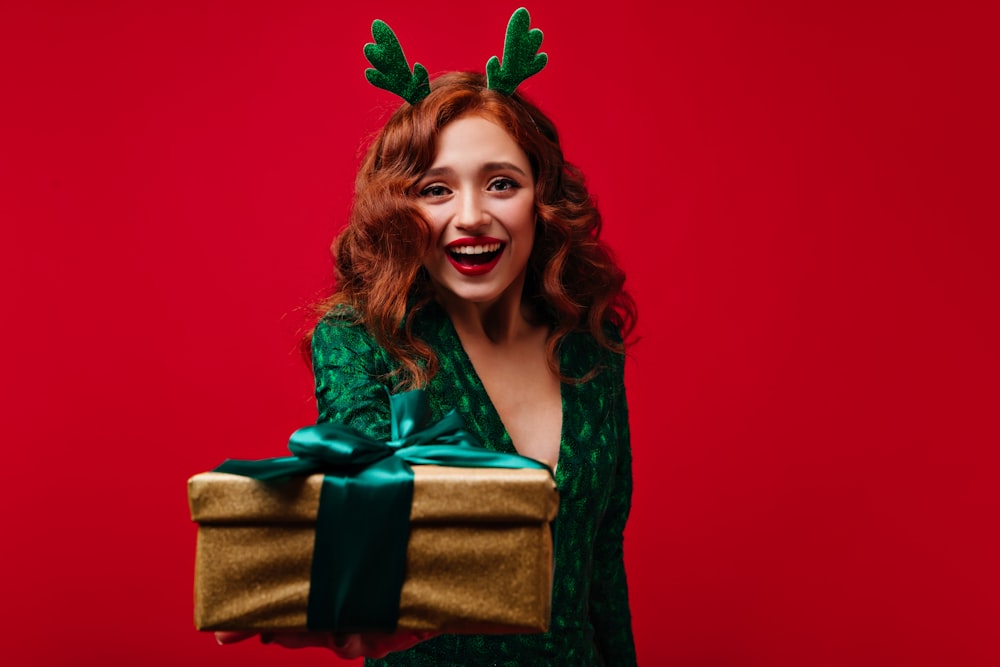 a woman wearing reindeer antlers holding a present