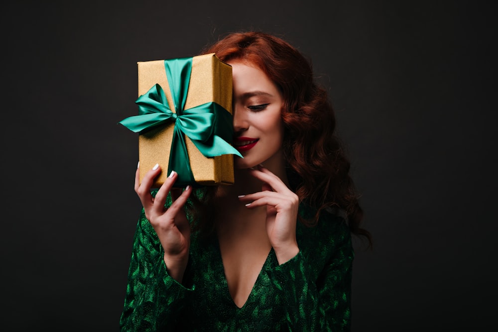 a woman holding a present box with a green bow