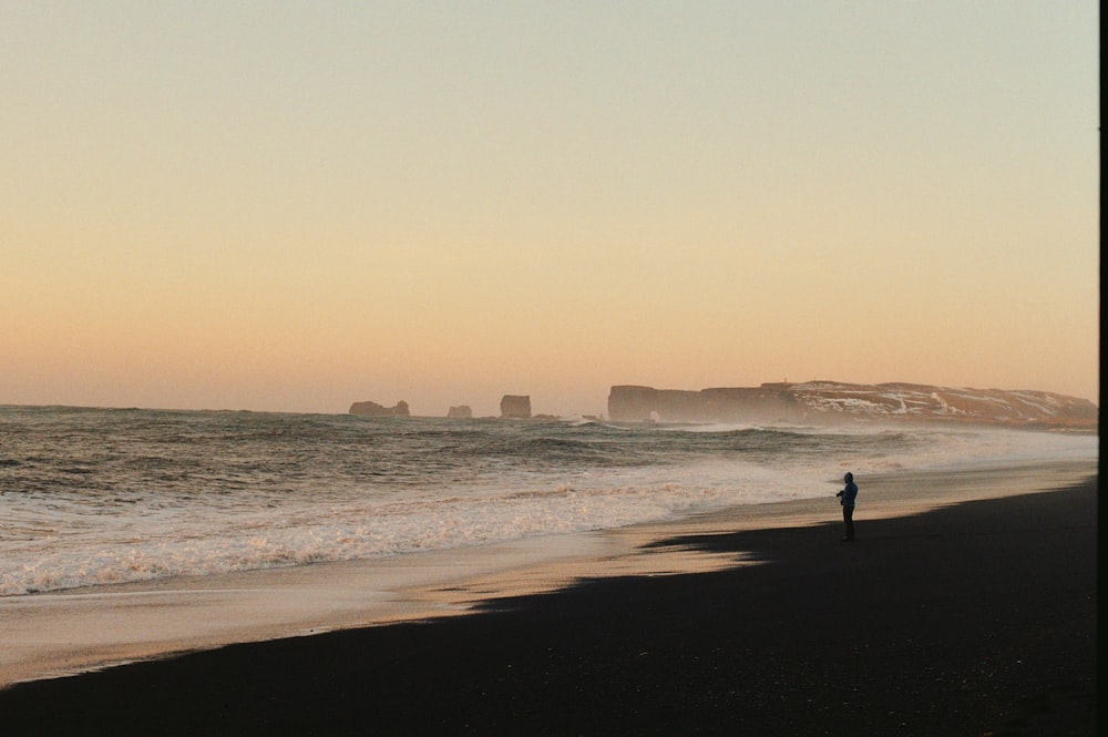 a person standing on a beach next to the ocean