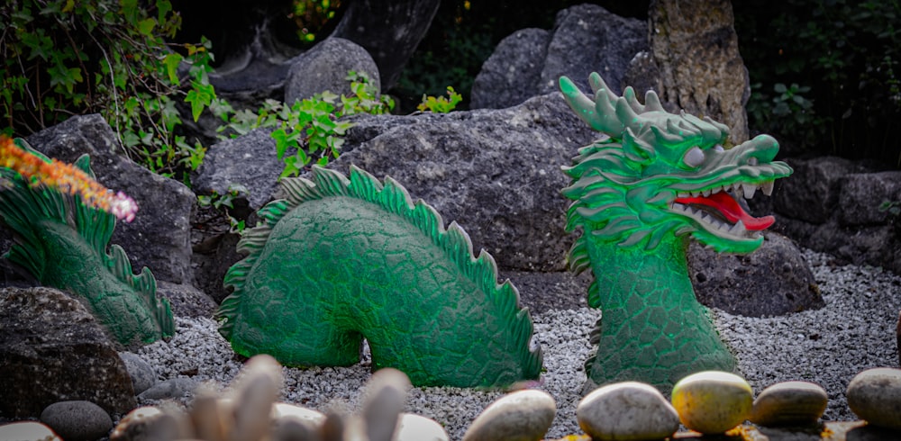 a couple of green statues sitting on top of a gravel field