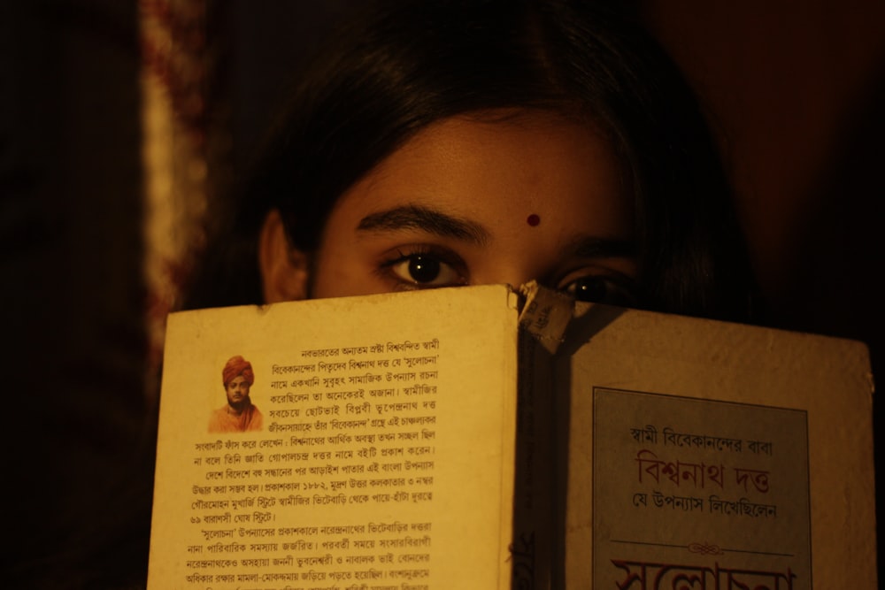 a woman holding a book in front of her face