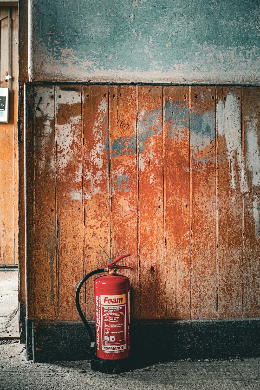 a red fire extinguisher sitting in front of a wooden door