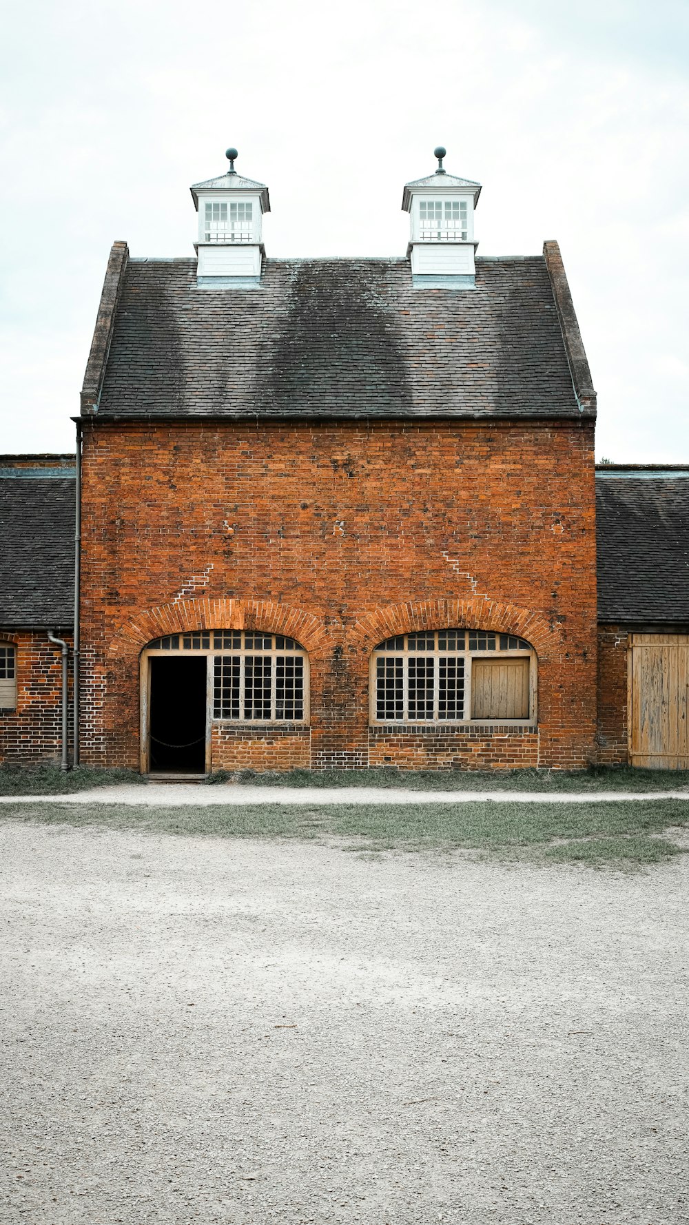 a red brick building with three windows and a black roof