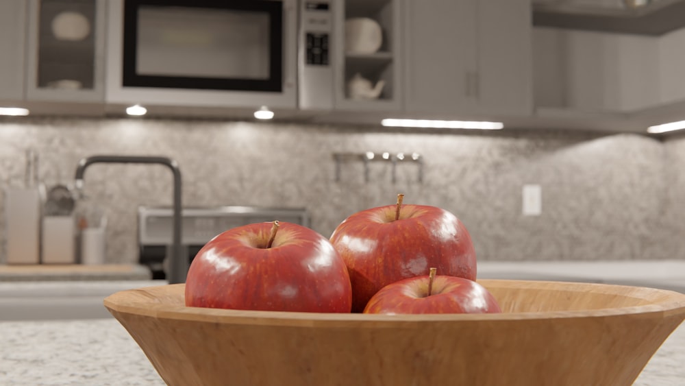 a wooden bowl filled with apples on top of a counter