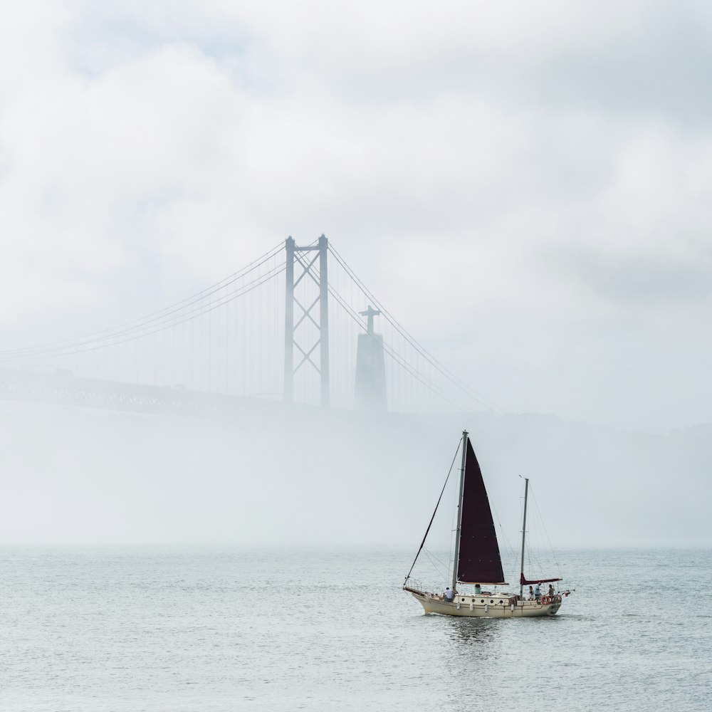 a sailboat on the water with a bridge in the background