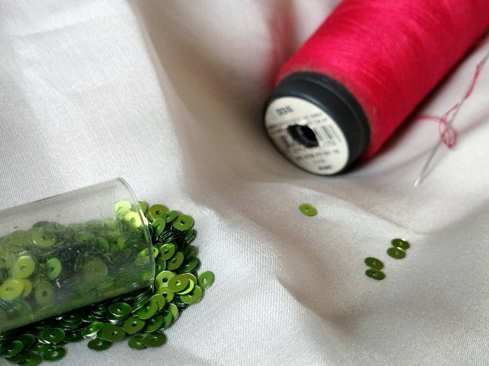 a spool of thread next to a spool of green beads