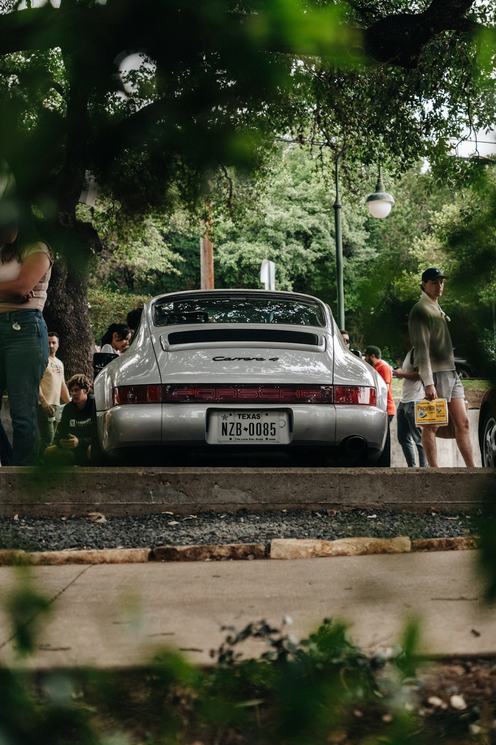 a group of people standing around a parked car