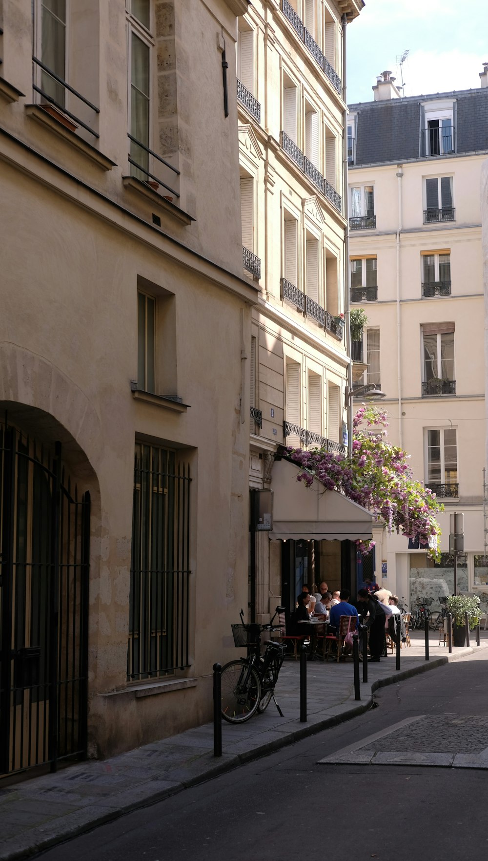 a city street lined with tall buildings and people sitting at tables