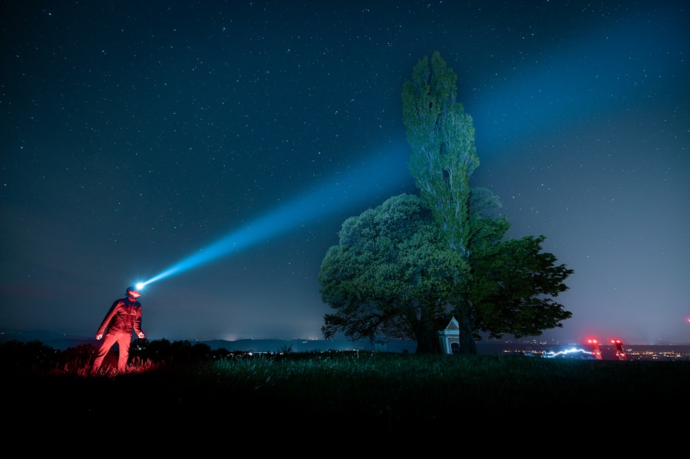 a person standing in a field with a flashlight in their hand