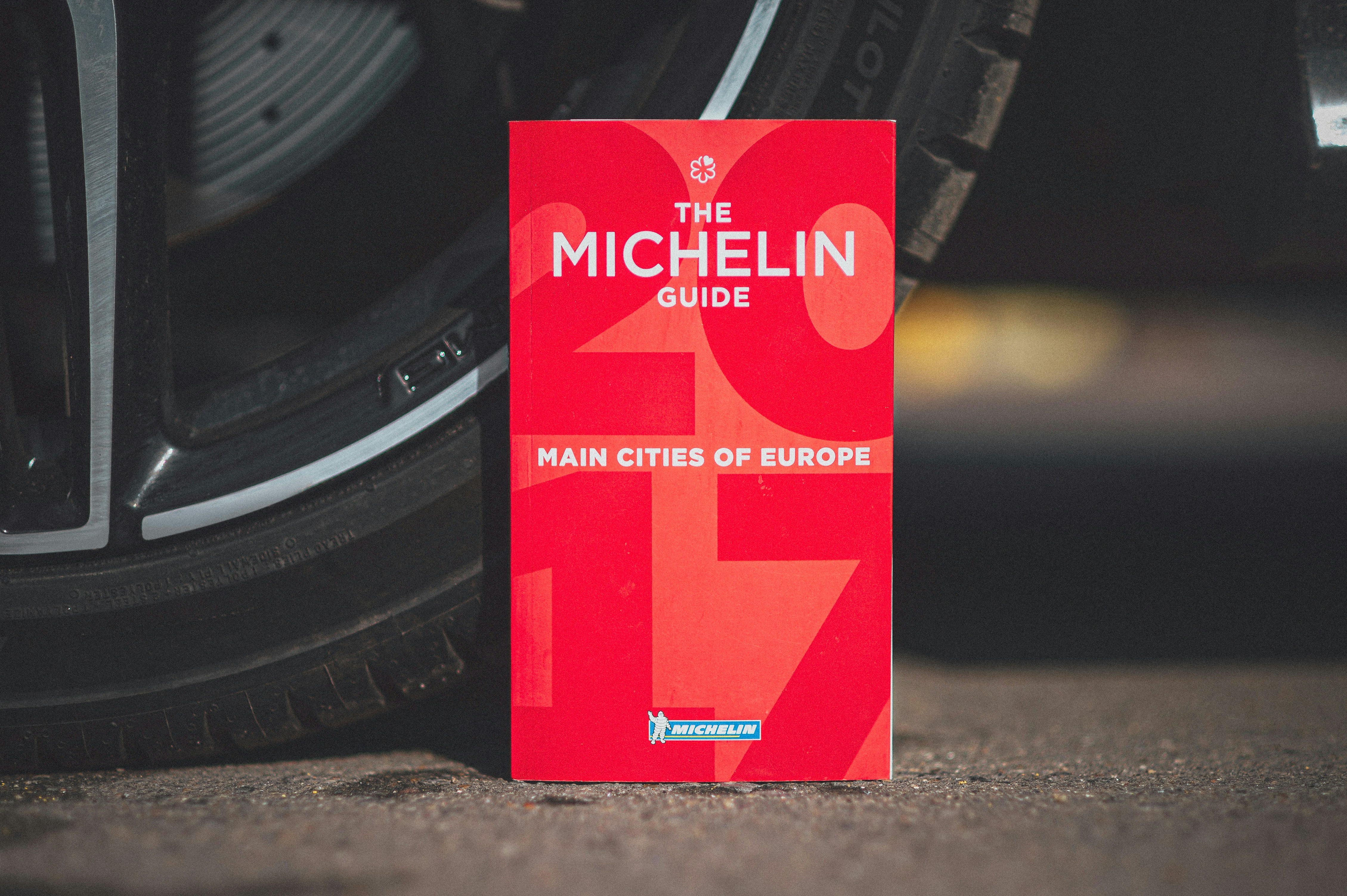 a red book sitting on the ground next to a tire, Michelin Red Guide