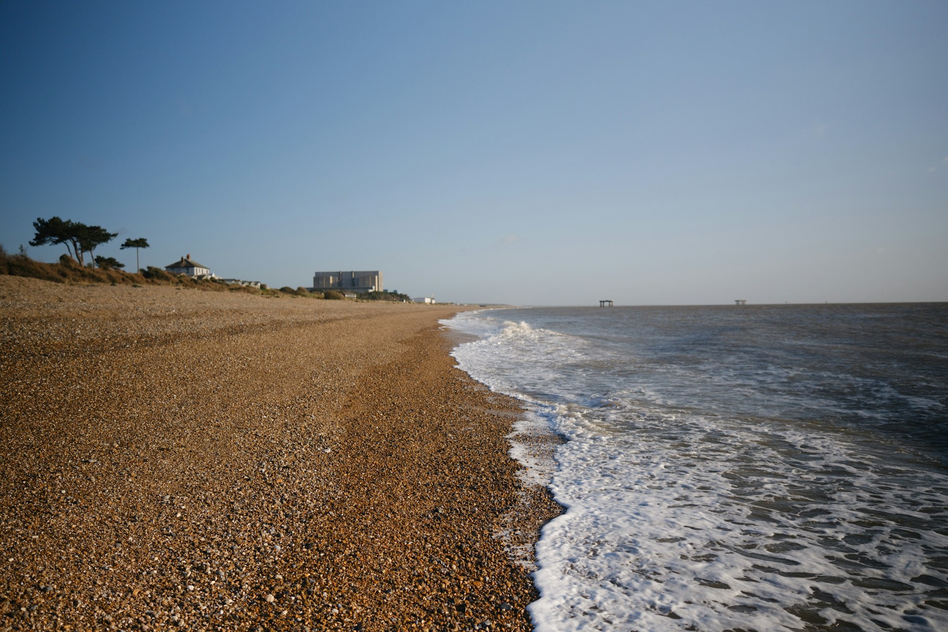 a sandy beach next to the ocean under a blue sky