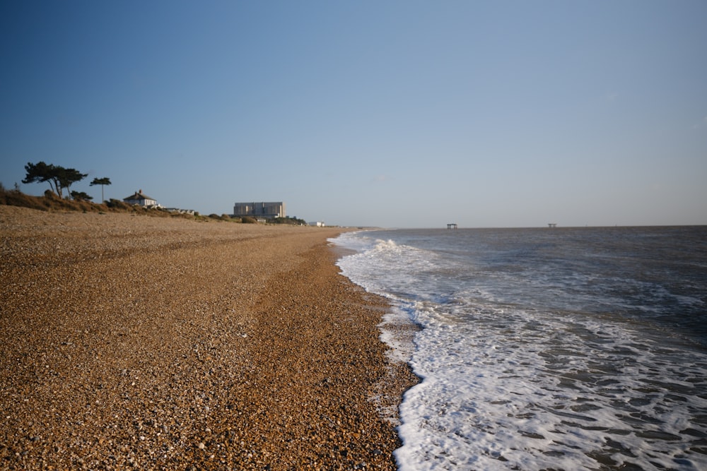 a sandy beach next to the ocean under a blue sky