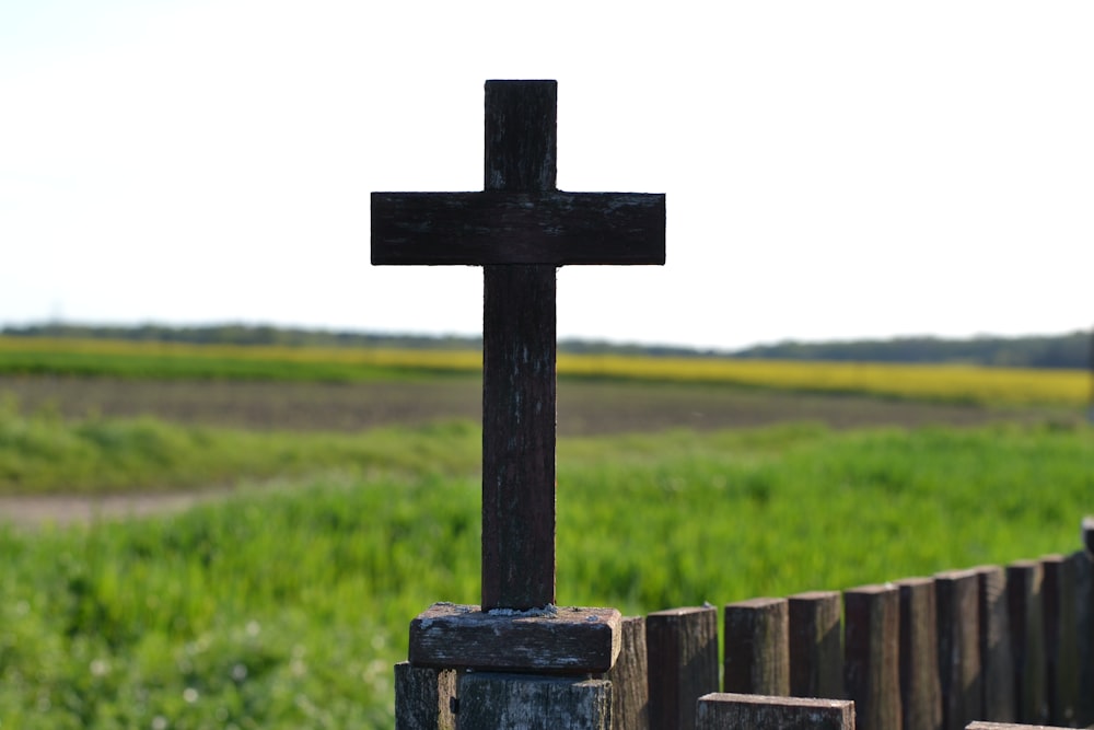 a wooden cross sitting on top of a wooden fence