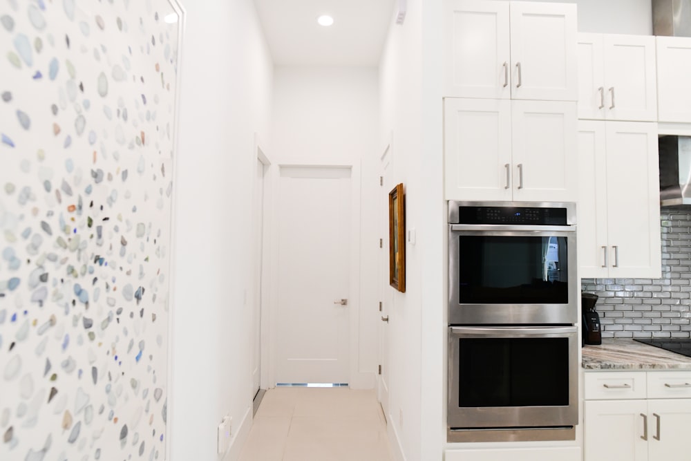 a kitchen with white cabinets and a stainless steel oven