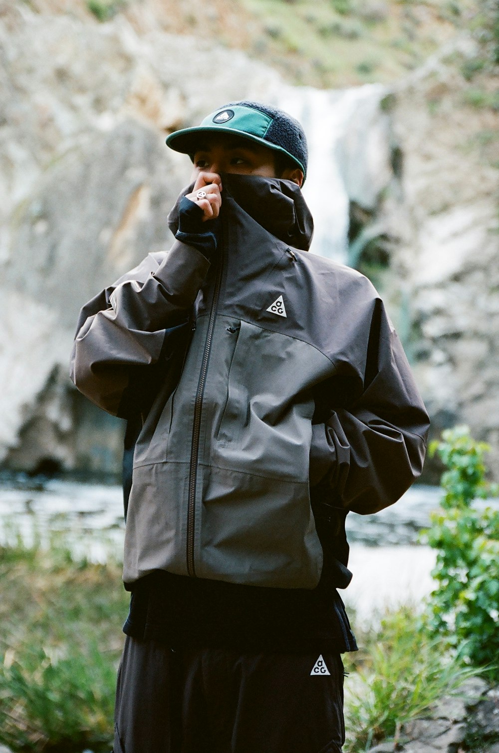 a man standing in front of a waterfall talking on a cell phone