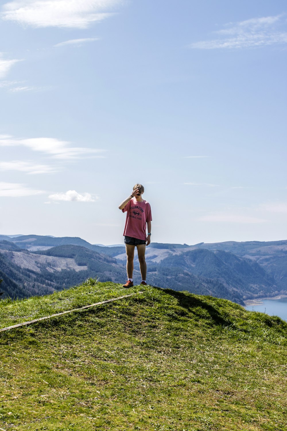 a woman standing on top of a grass covered hill