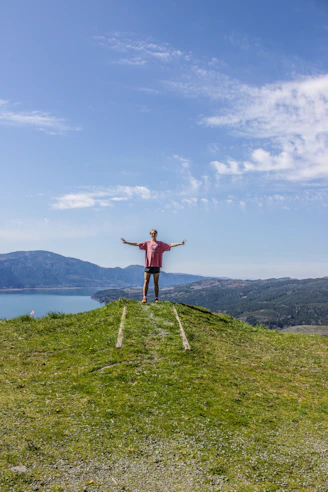 a man standing on top of a grass covered hill