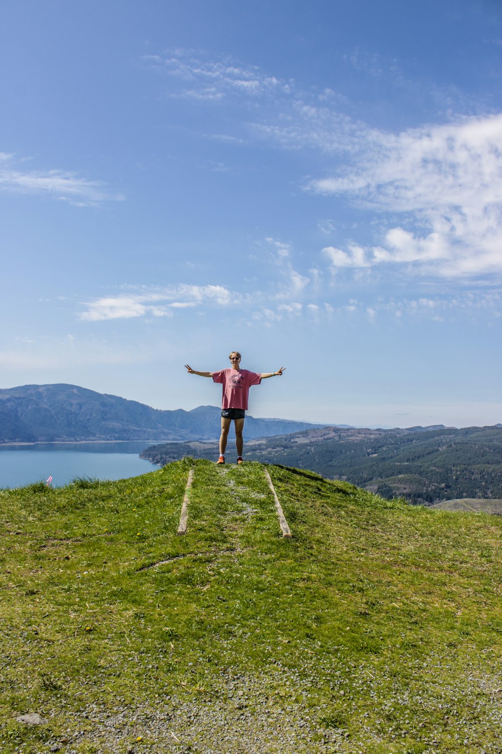 a man standing on top of a grass covered hill