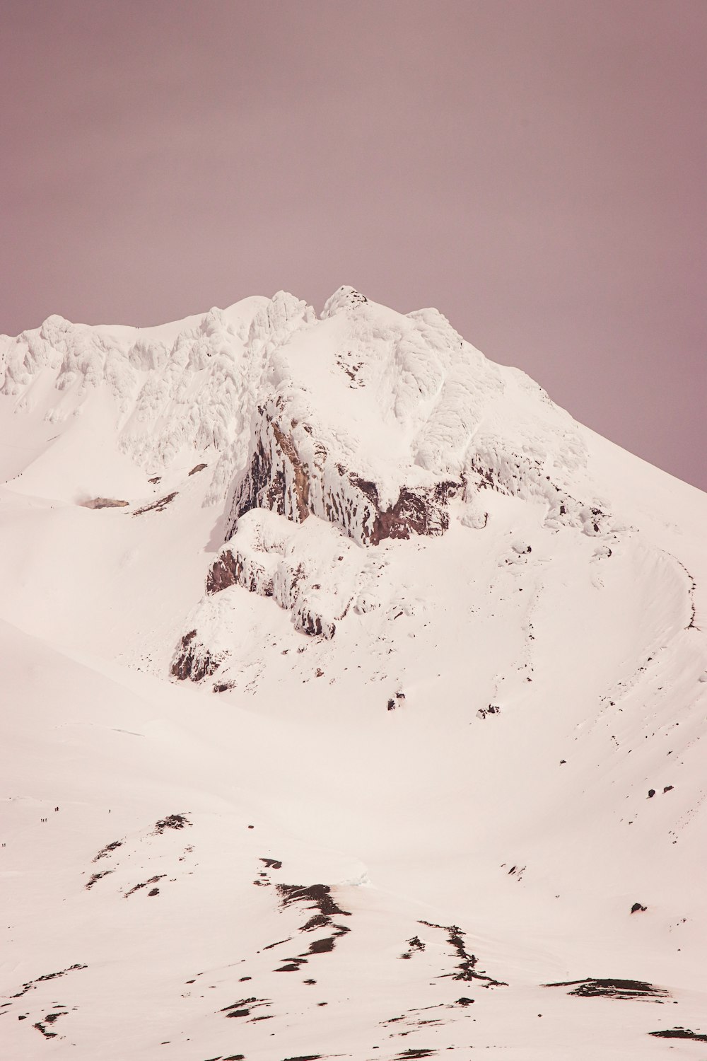 a mountain covered in snow under a cloudy sky