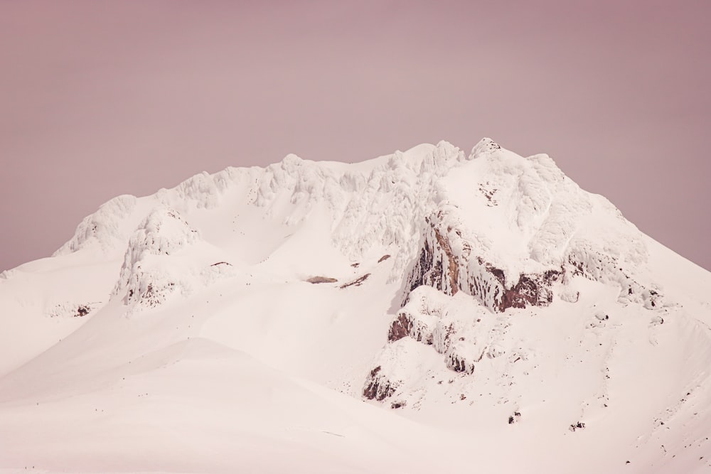 a mountain covered in snow under a cloudy sky