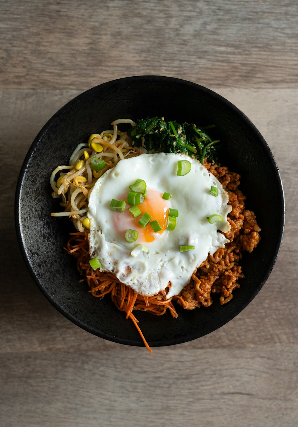 a black bowl filled with noodles and an egg