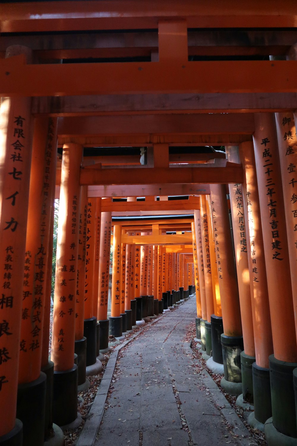 a walkway lined with tall orange pillars with writing on them