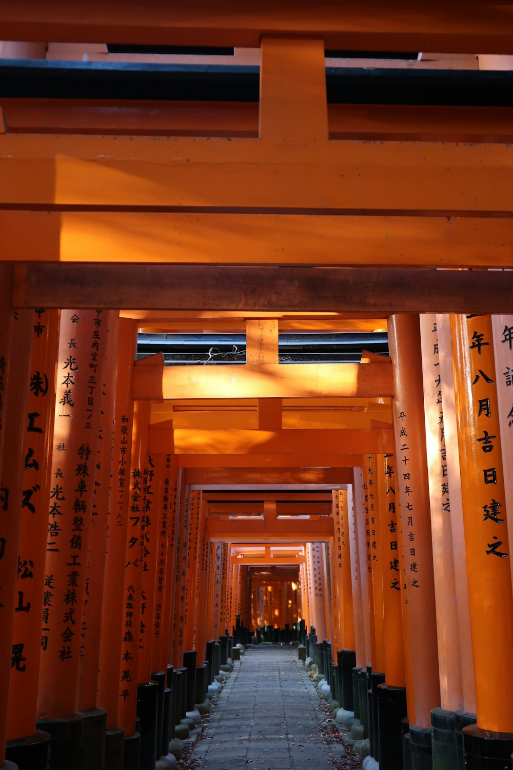 a walkway lined with tall orange pillars with writing on them
