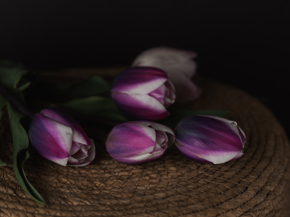 a bunch of purple tulips sitting on top of a straw hat
