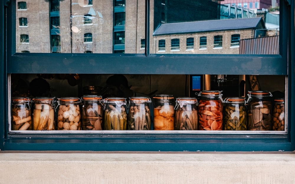 many jars of food are lined up in a window
