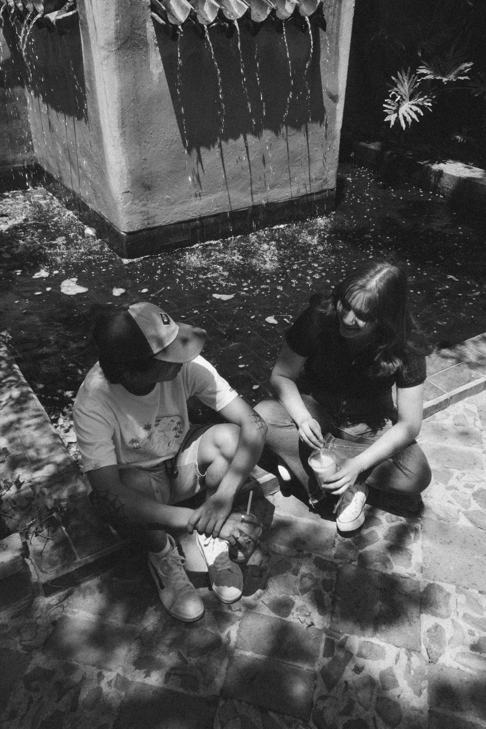 A couple sitting close together on the ground, leaning in conversation