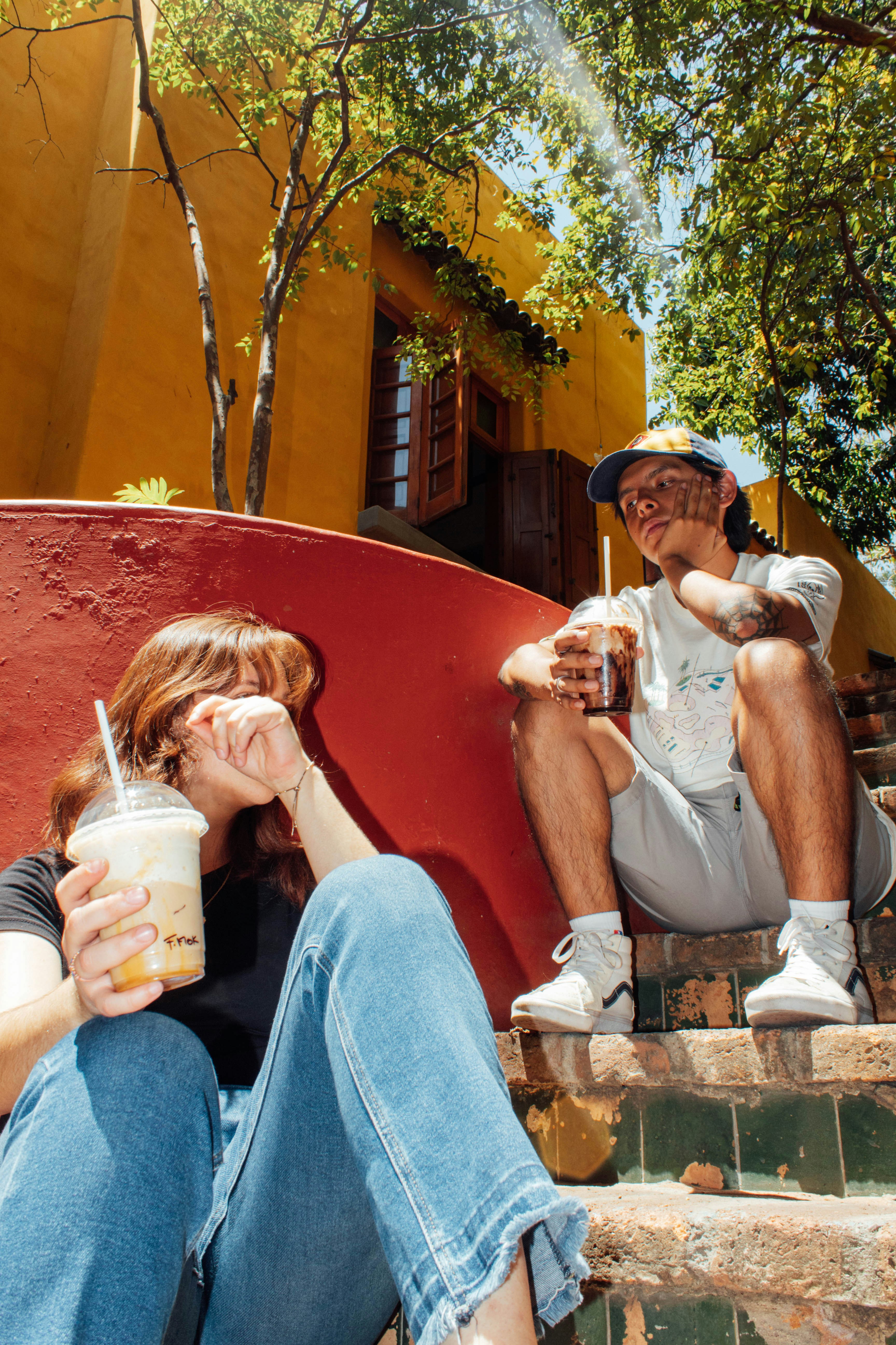 a man and a woman sitting on steps drinking beverages