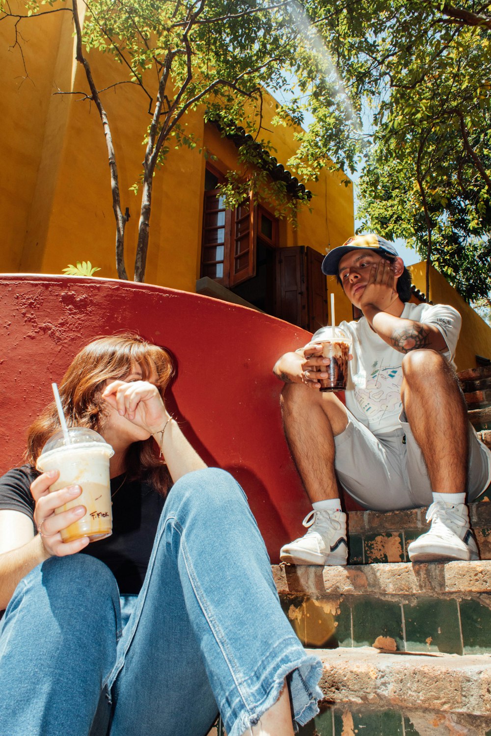 a man and a woman sitting on steps drinking beverages