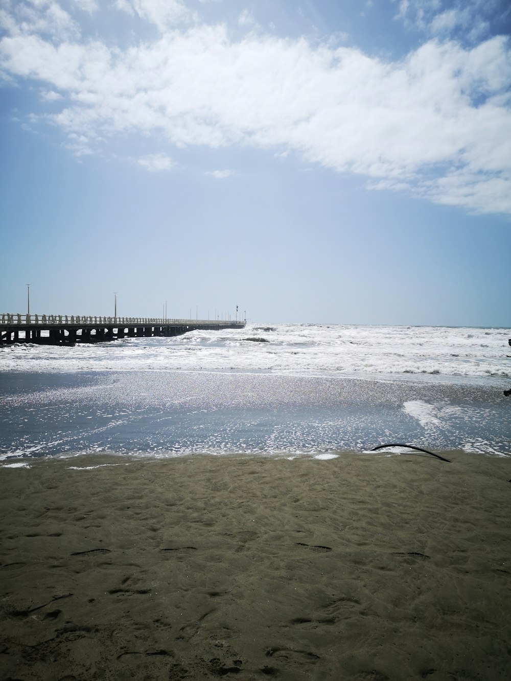 una playa de arena con un muelle a lo lejos