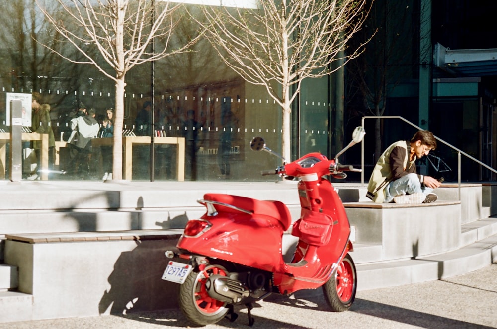 a red scooter parked on the sidewalk in front of a building