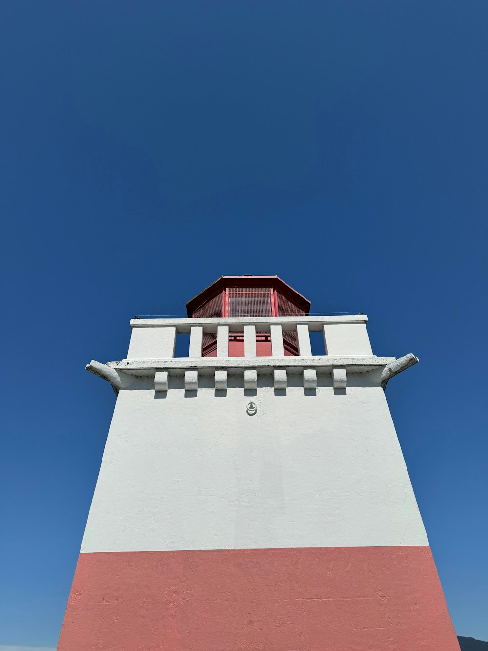 a red and white lighthouse with a blue sky in the background