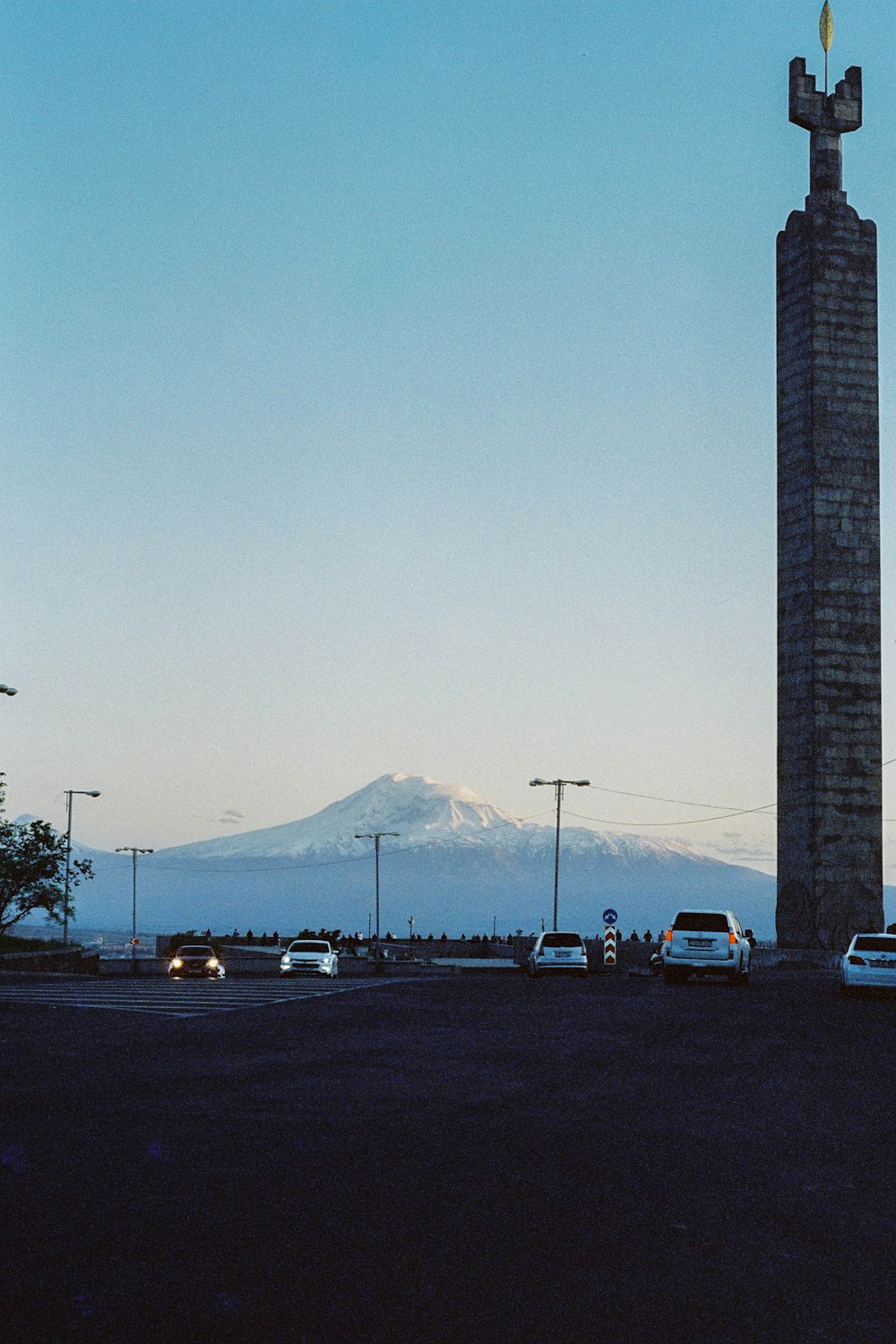 cars are parked in a parking lot in front of a tall monument