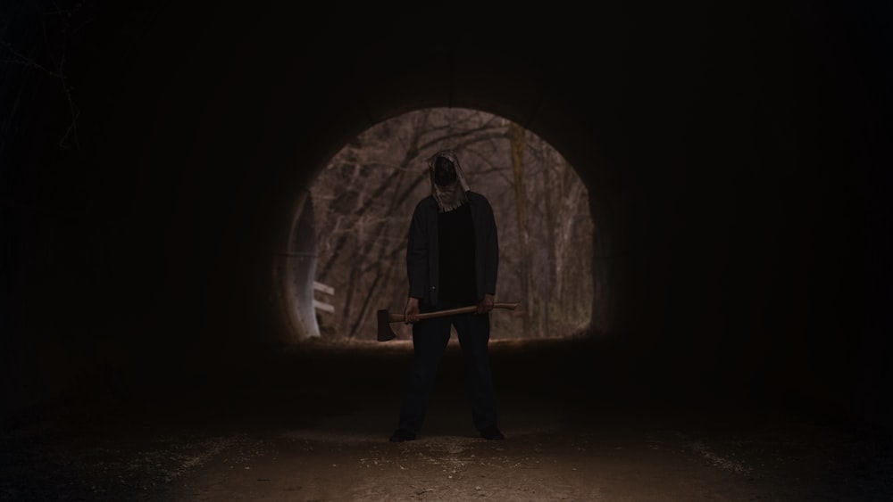 a man holding a hammer in a dark tunnel