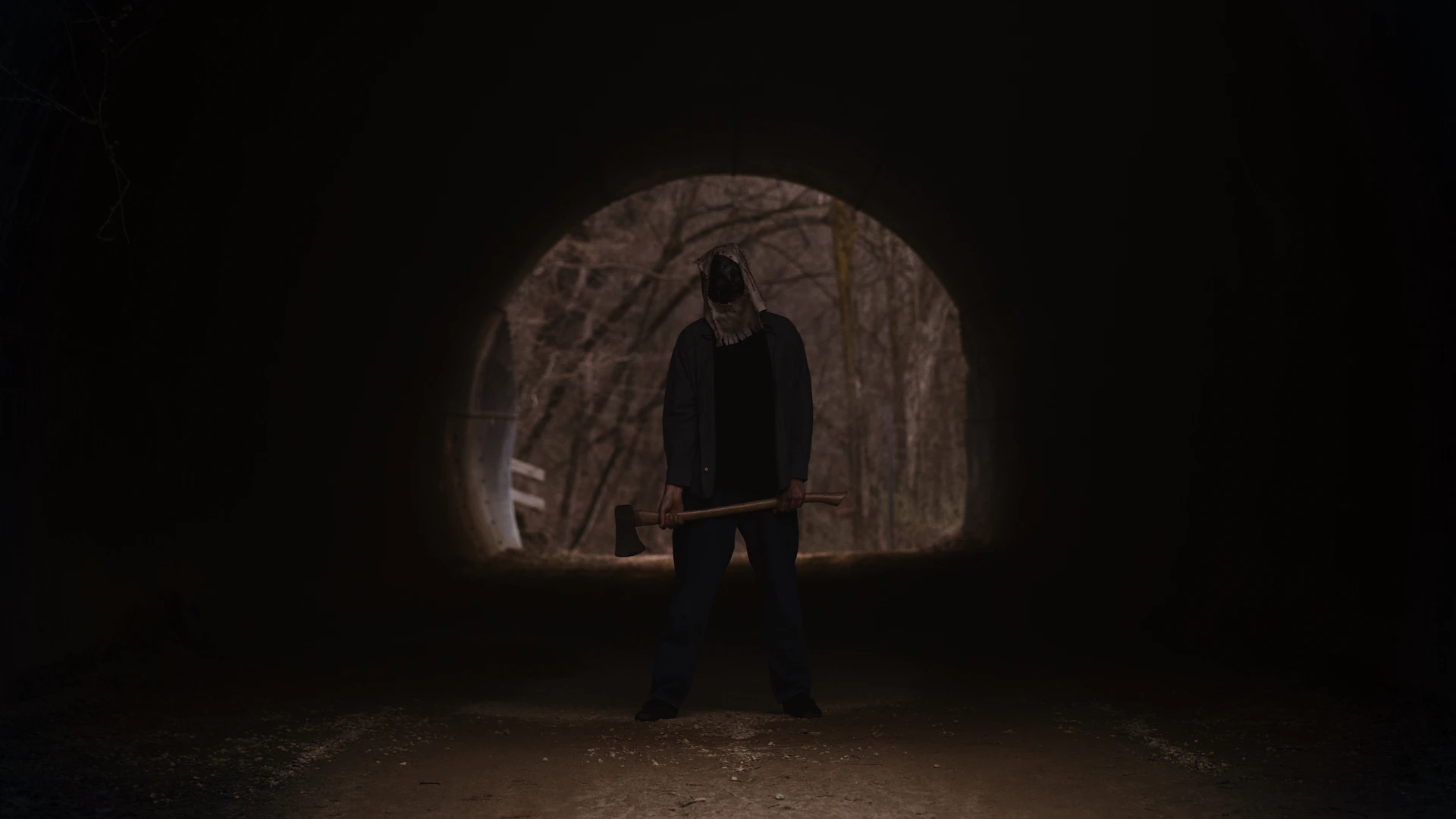 a man holding a hammer in a dark tunnel