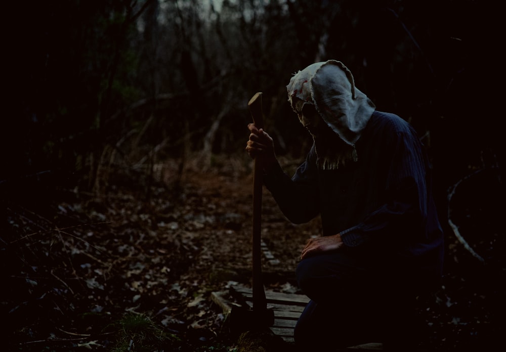 a person in a white mask is sitting on a bench in the woods