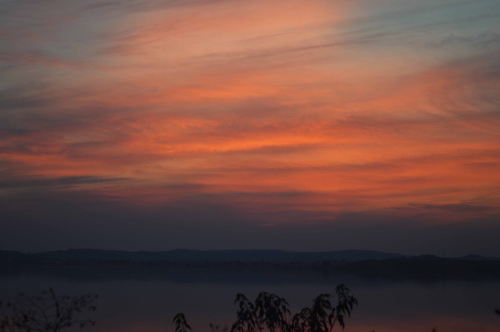 a view of a sunset with clouds and mountains in the distance