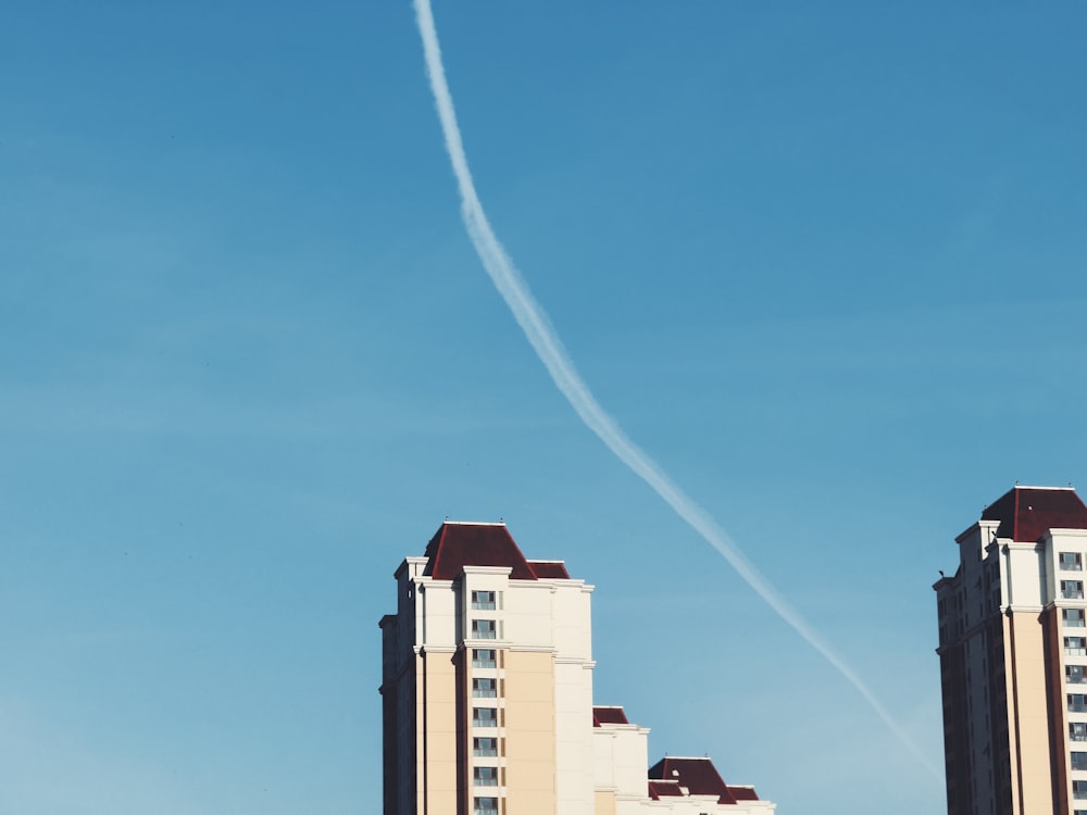 a plane flying in the sky over some tall buildings