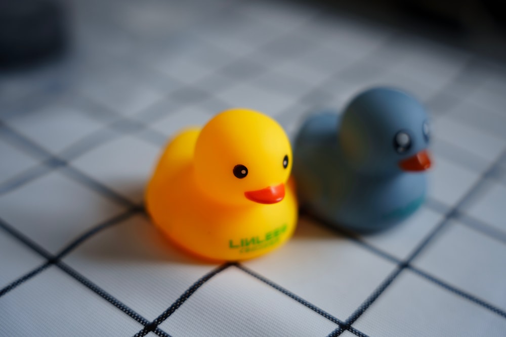 a couple of rubber ducks sitting on top of a tiled floor