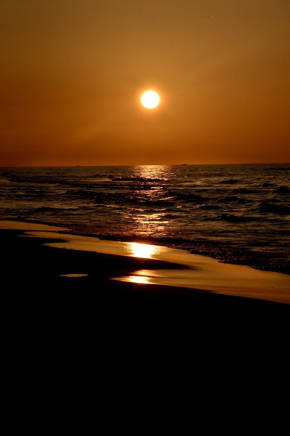 the sun is setting over the water at the beach