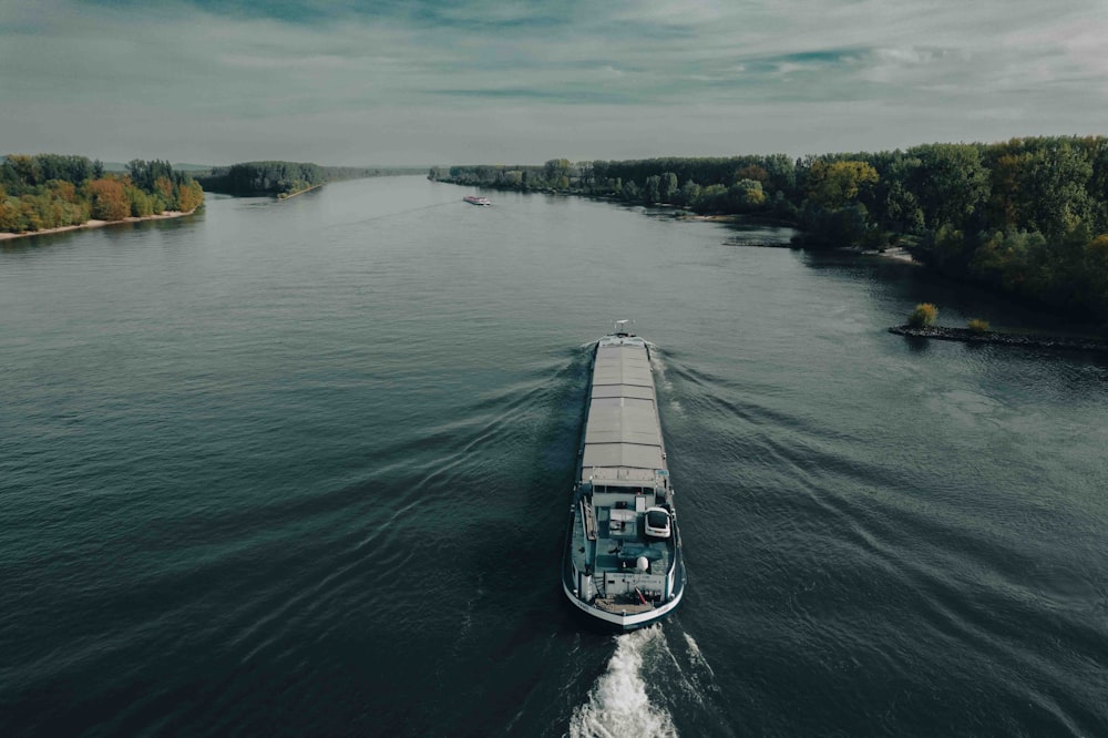 a boat traveling down a river next to a forest