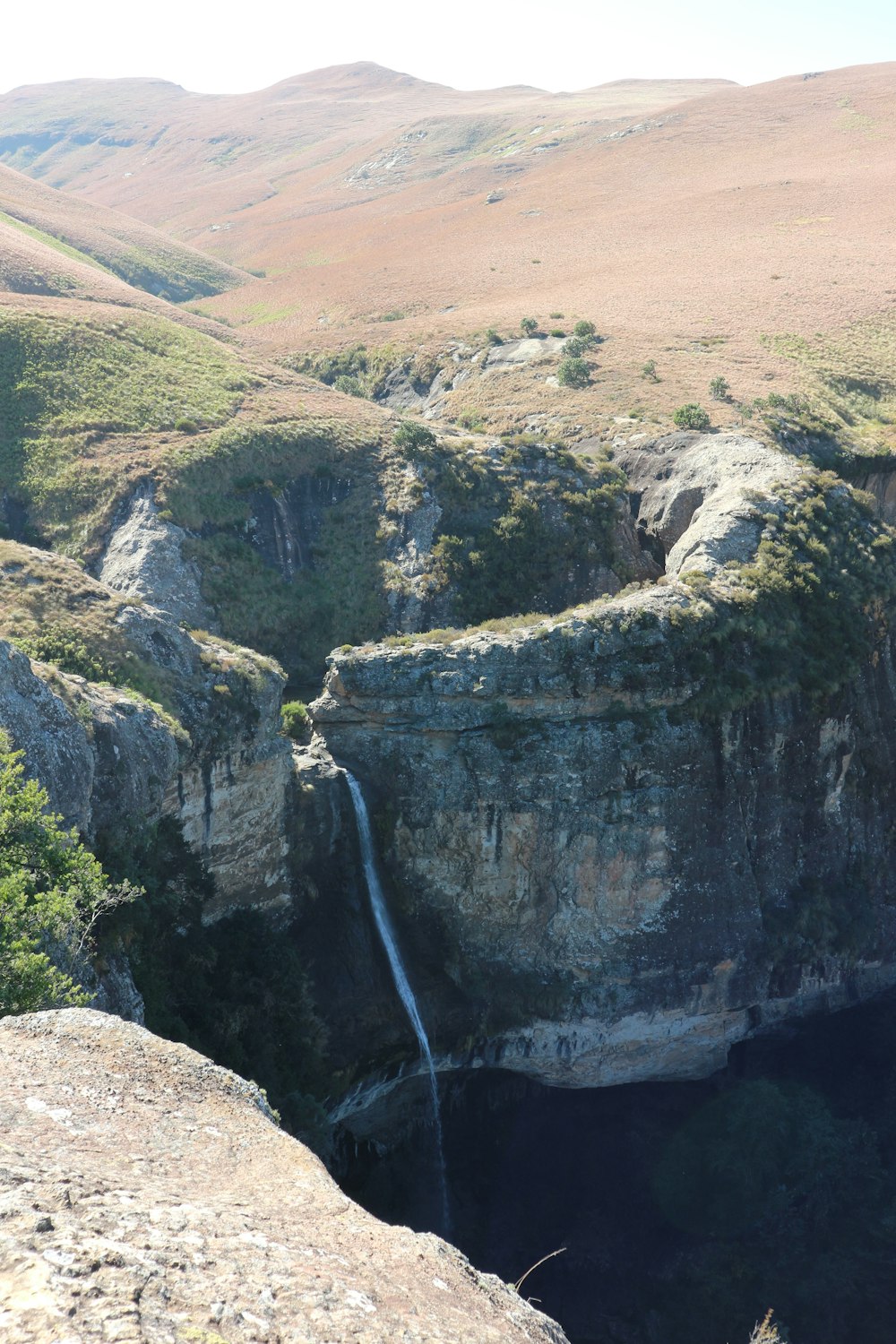 a man standing on top of a cliff next to a waterfall