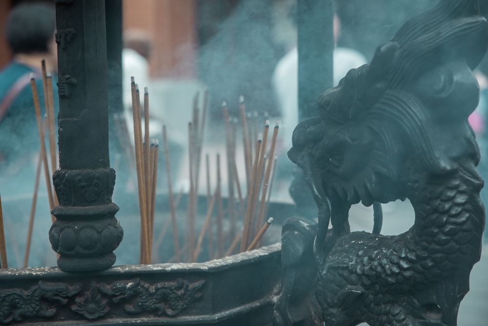 a dragon fountain with incense sticks sticking out of it