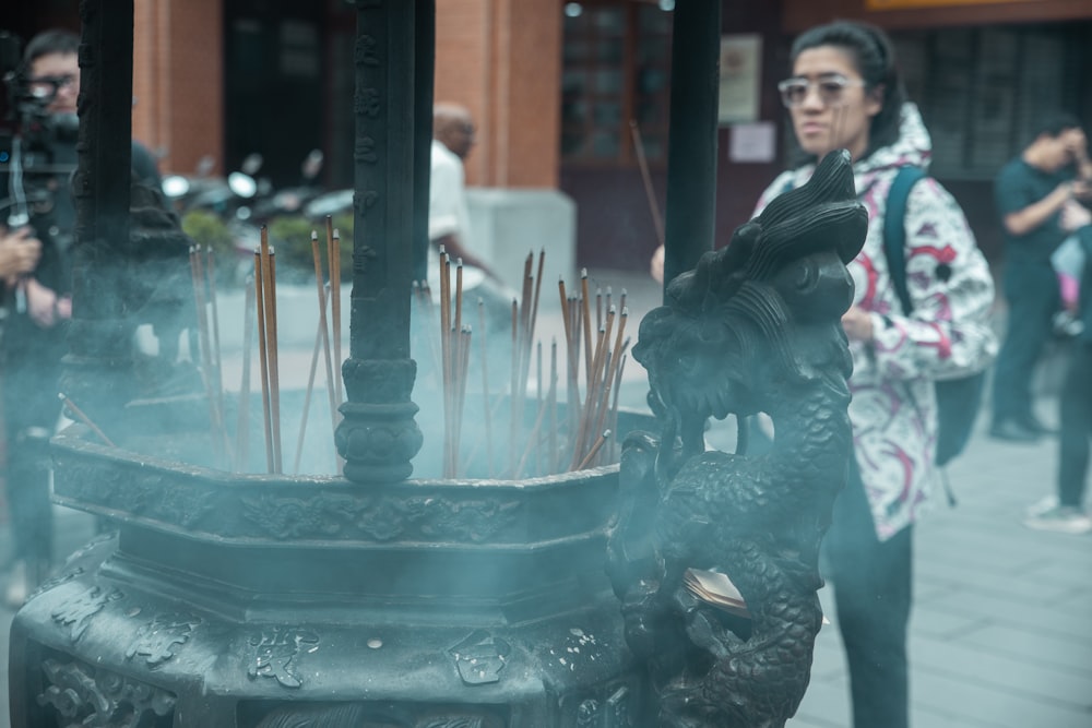 a group of people standing around a fountain with sticks sticking out of it