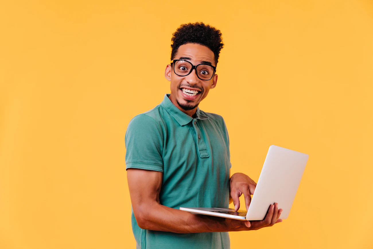 A man in glasses grinning at his laptop.
